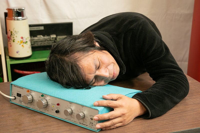 「睡眠学習　SLシータップ model-2001」に実際に寝てみている冨永さん