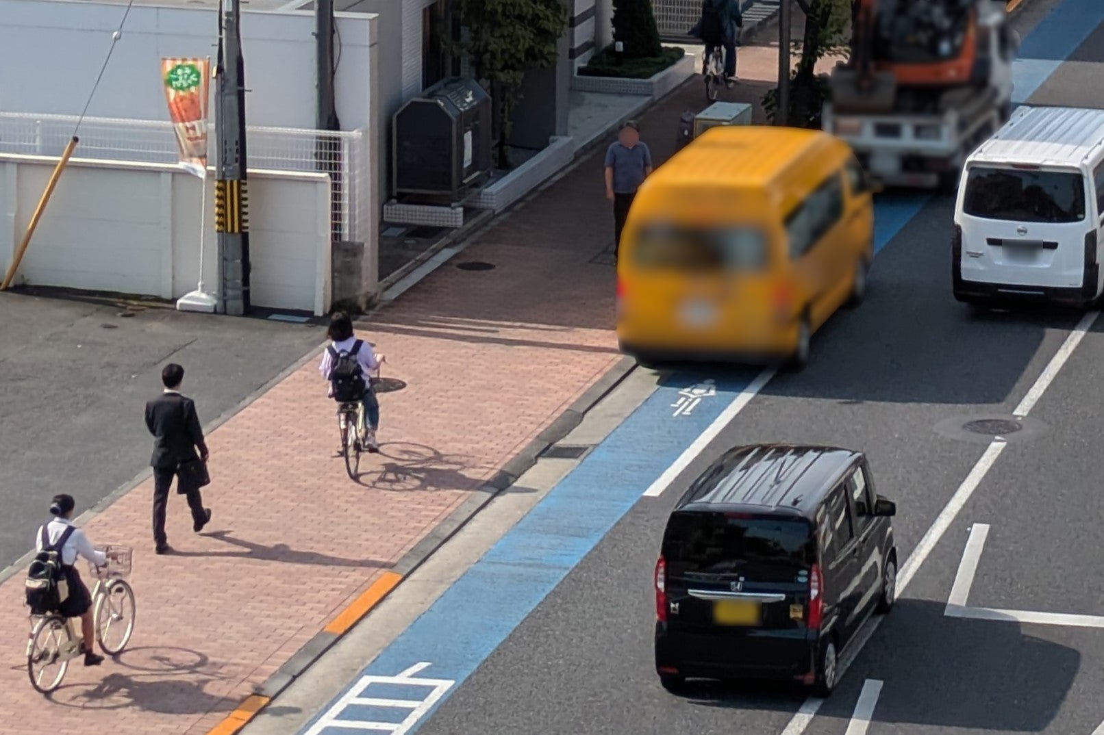 自転車レーンに停車する車と、歩道を走る自転車