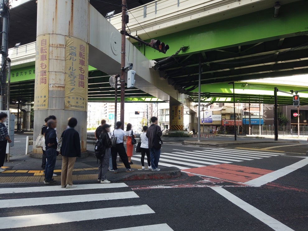 交差点内の交通島で信号待ちをする歩行者