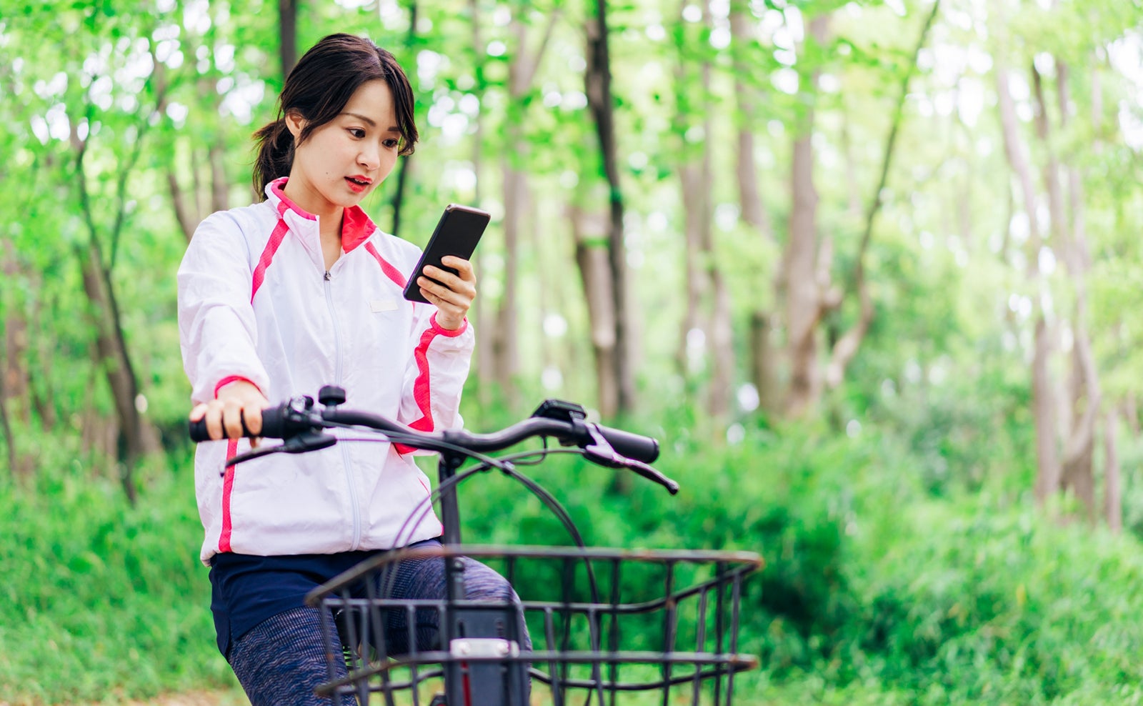 自転車に乗りながらスマホを使う女性 