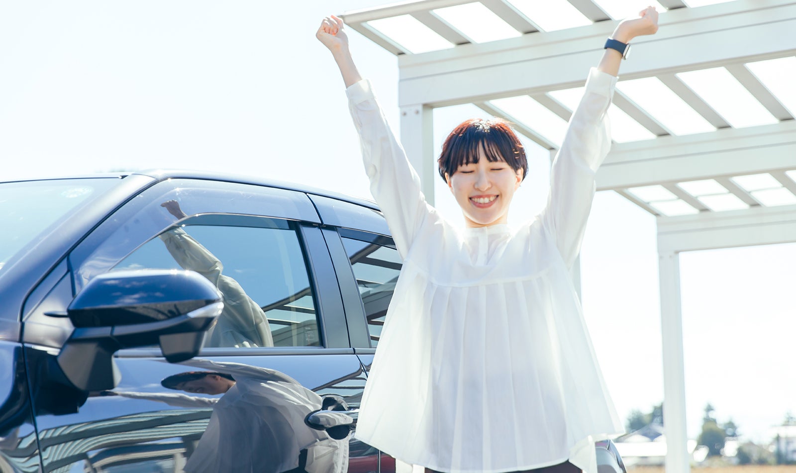 運転の合間にクルマの横でストレッチをする女性