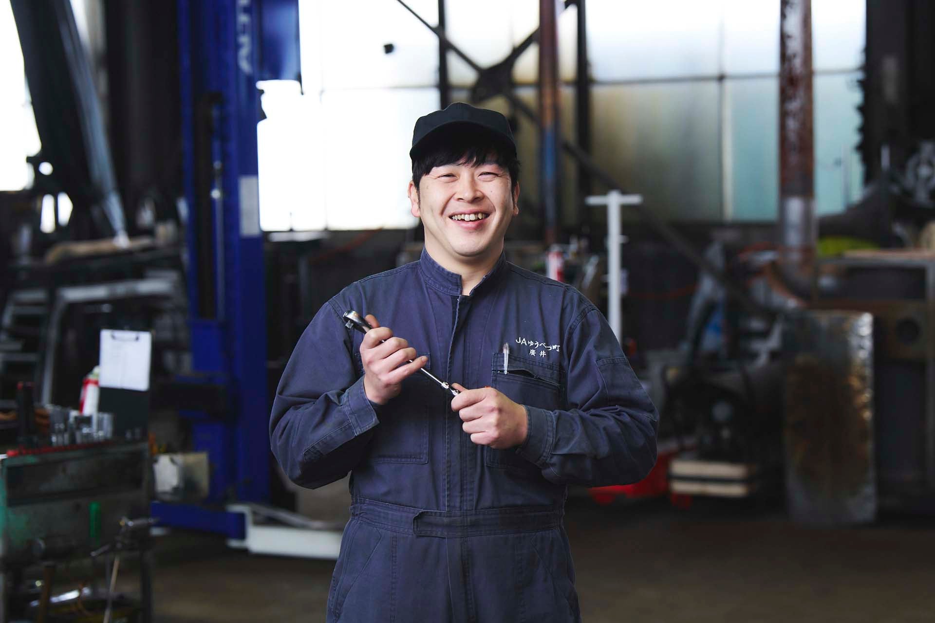 整備道具を手に笑顔ではにかむ廣井晃彦さん