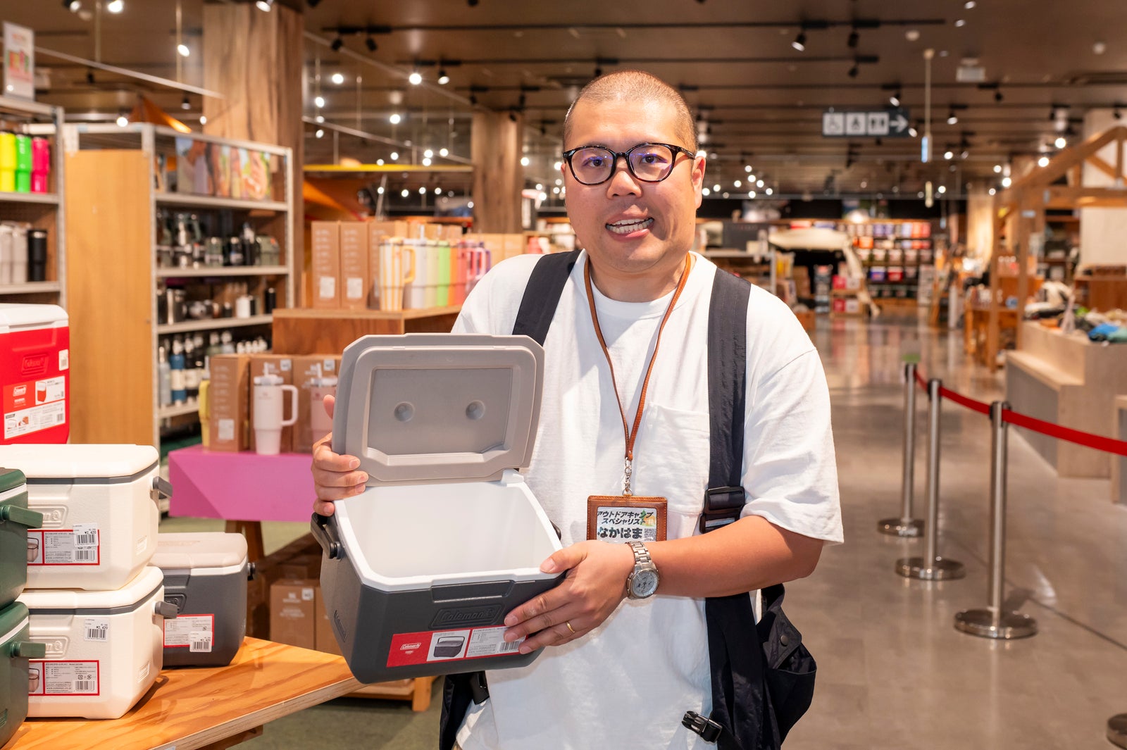小型クーラーボックスを手にするアウトドアショップ店員