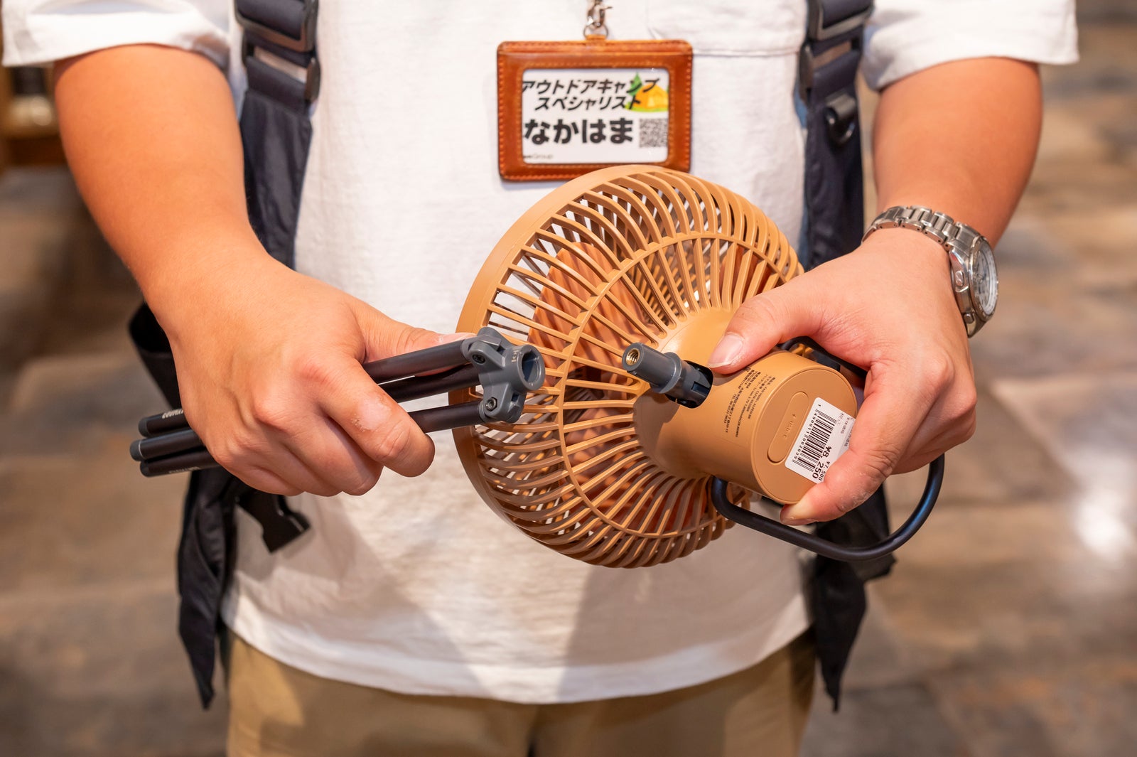 サーキュレーターの三脚を取り外して説明する店員