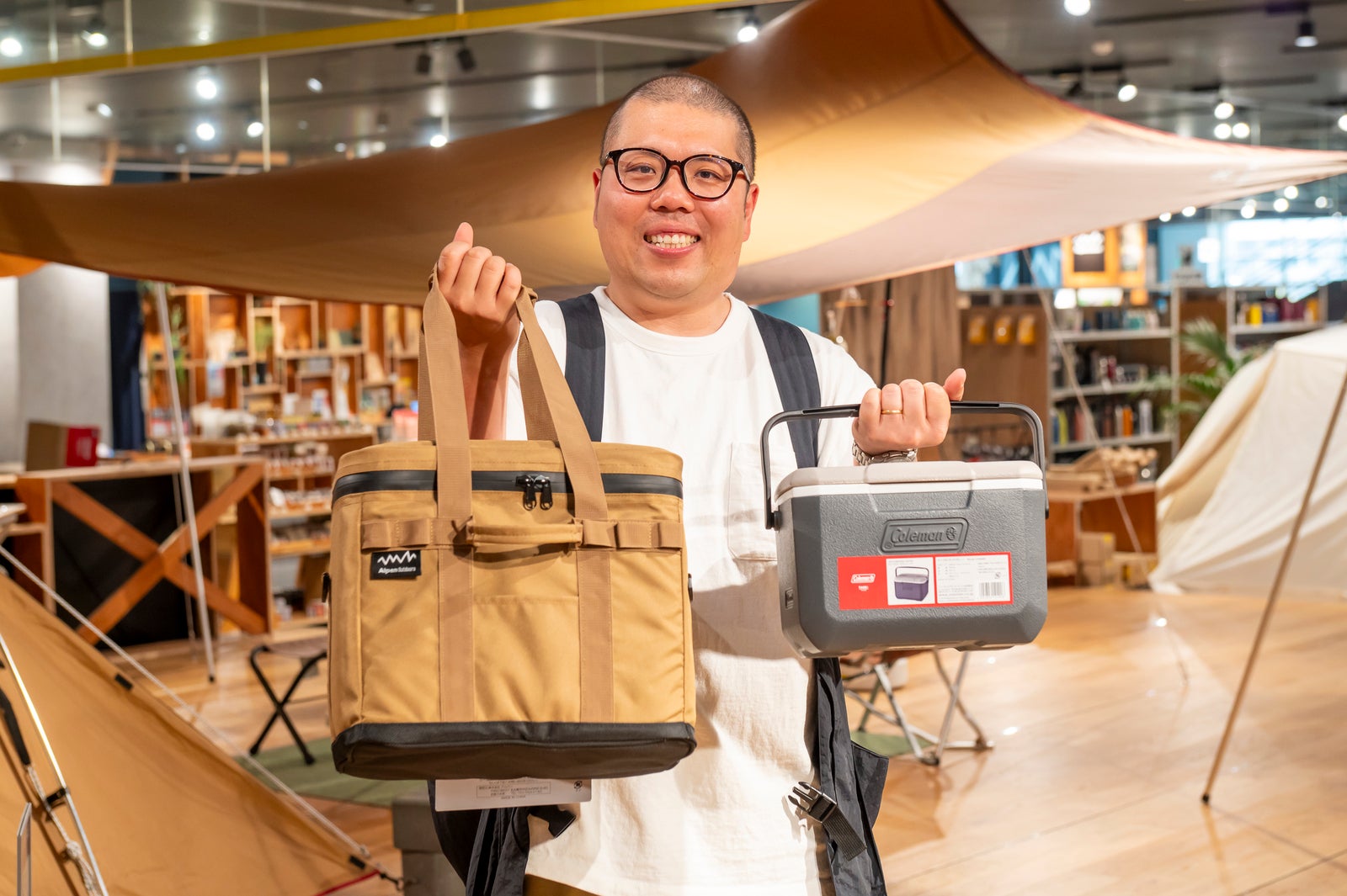 両手に1つずつクーラーボックスを持ってポーズを取る店員