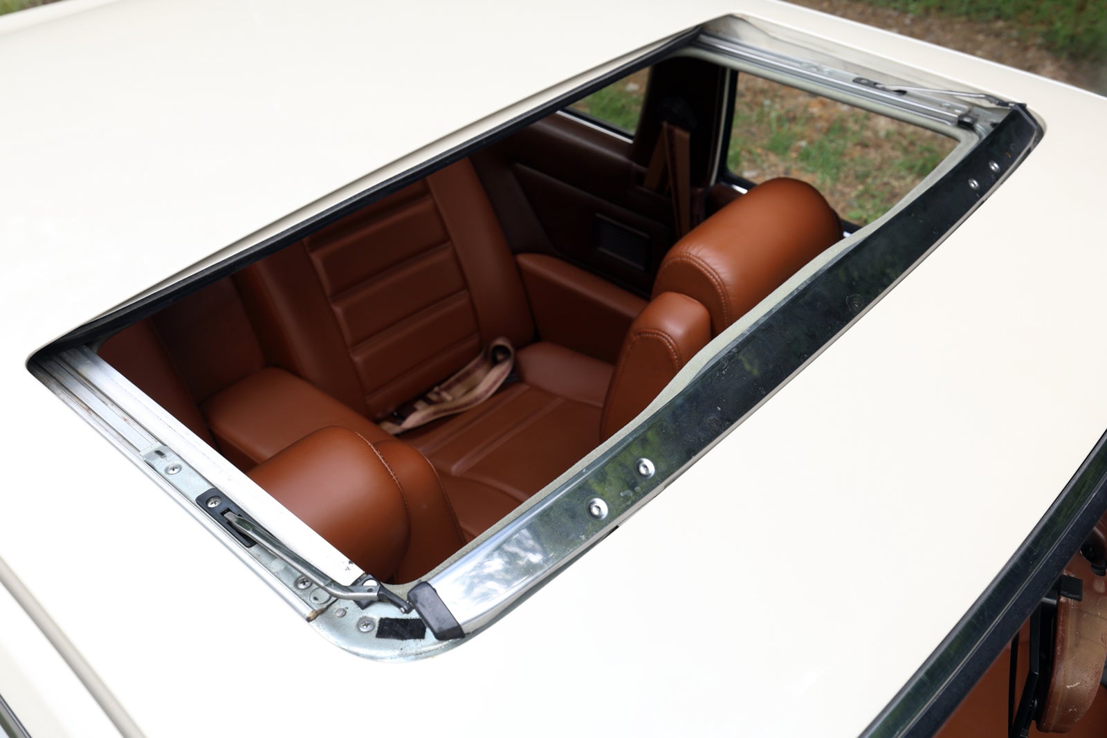 初代ソアラのサンルーフ越しに見た車内。茶色のレザーシートが特徴的で、後部座席とドアパネルが映っている
