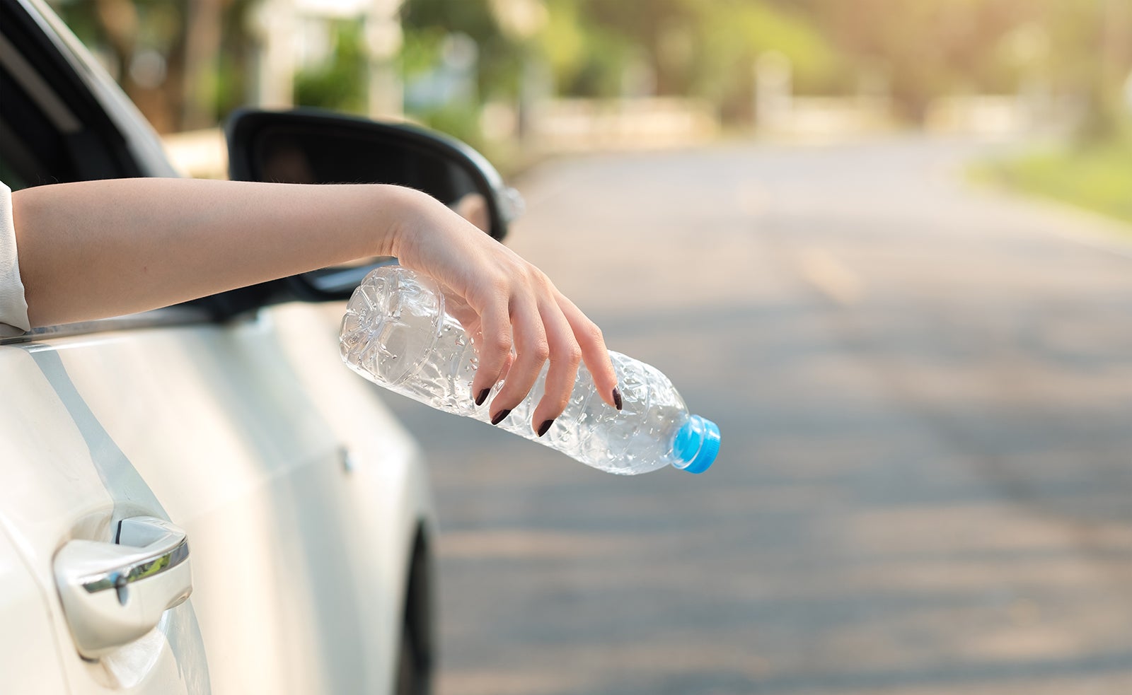 車窓からペットボトルを捨てようとしている女性