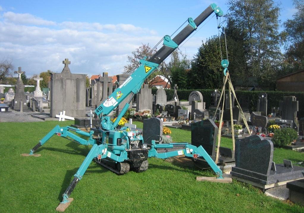 かにクレーンで墓石設置作業している写真
