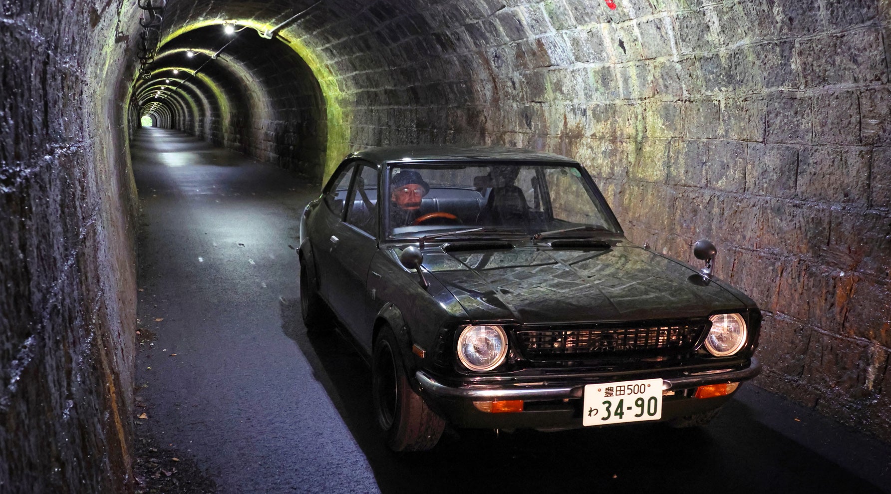 1974年式トヨタ・カローラレビンTE27型モスグリーンが石造りのトンネルを走行する。Vintage club by KINTOからレンタルした車両