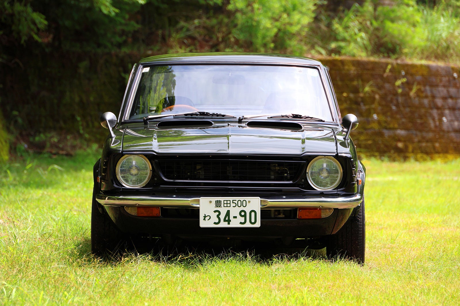 草地に停車した1974年式トヨタ・カローラレビンTE27型。モスグリーンのフロントビュー。ナンバープレート「34-90」