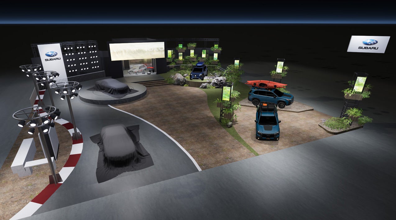 スバル（SUBARU）のジャパンモビリティショー2025ブースの俯瞰イメージCG。ブースは舗装路と自然の土や植物を組み合わせたデザイン。中央には大きなモニターがあり、手前のステージにはカバーがかけられた2台の車両が置かれている。奥の展示スペースには、青いSUVとオレンジのスポーツカーなど、数台の車両が展示されている。ブース全体が、自然環境とモータースポーツを融合させたような空間構成になっている。