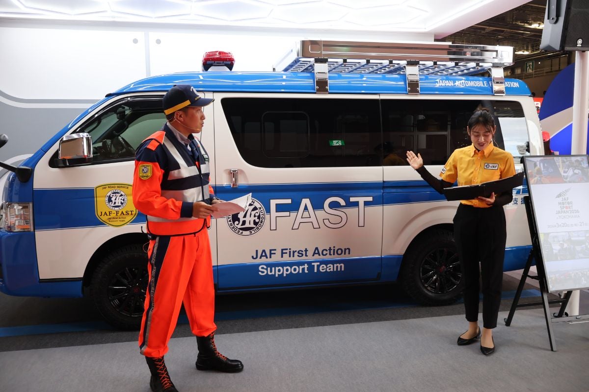 Japan Mobility ShowのJAFブースのステージイベントの様子。ロードサービス隊員とMCが登壇し、説明を行っている