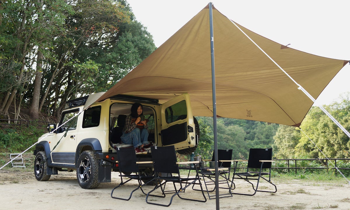 四駆車のリアにオープンタープを取り付けて女性がくつろいでいる写真