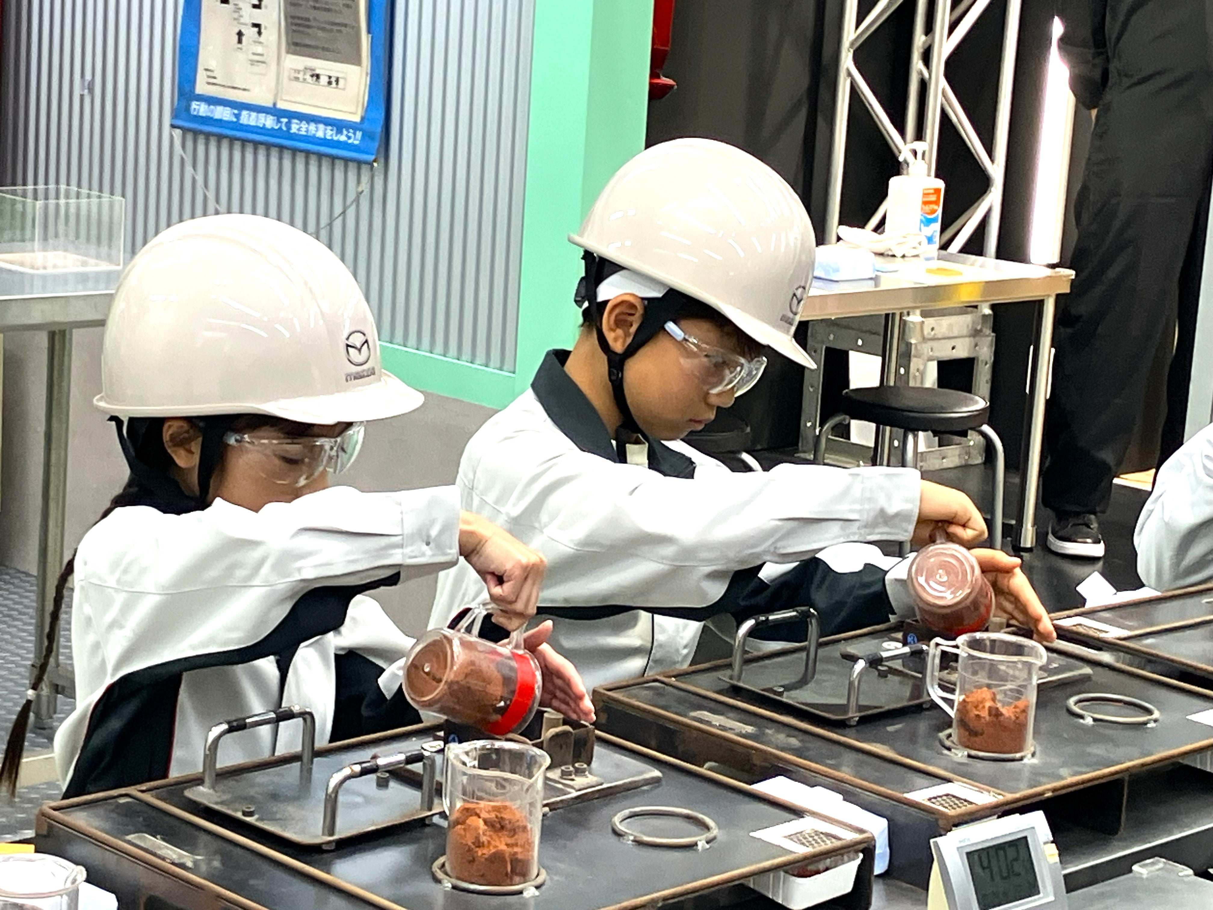 マツダブースでミニカーの砂型鋳造・磨き・塗装職人の仕事を体験する子ども