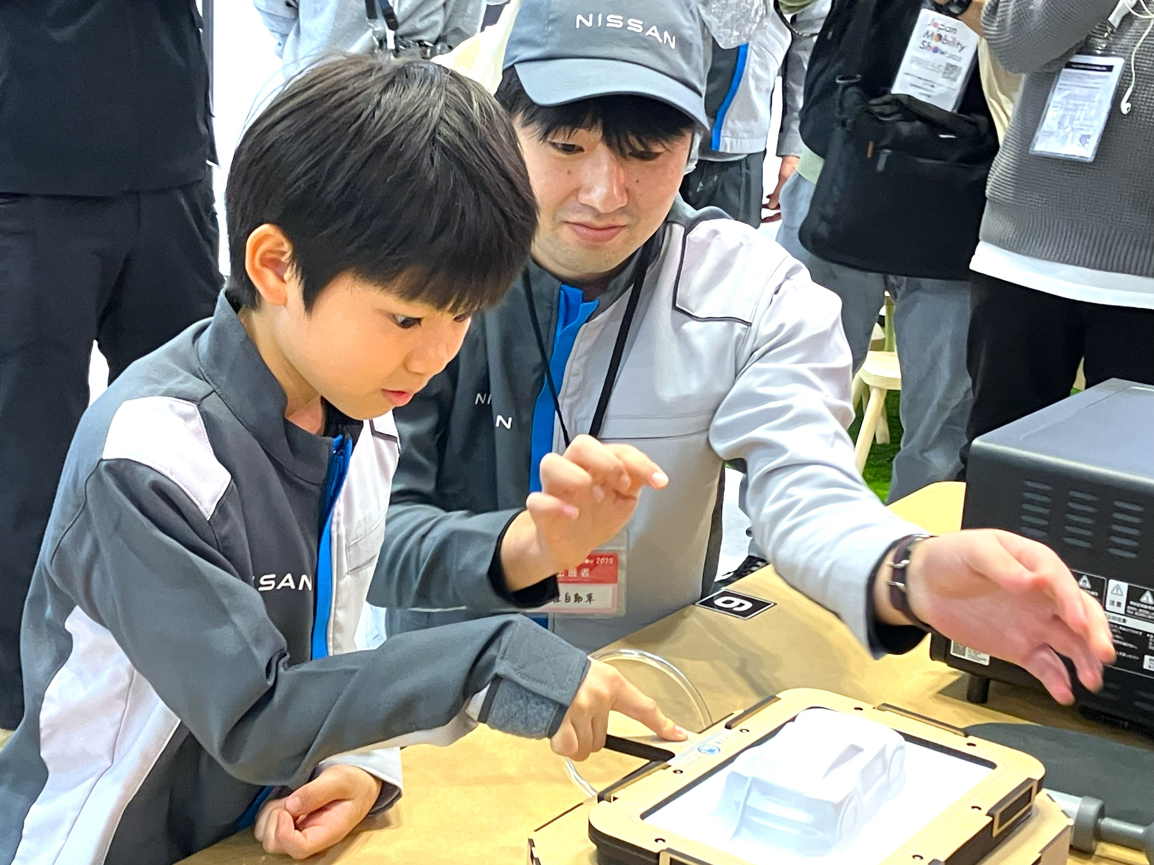日産ブースでカーボディの成型体験をする子供