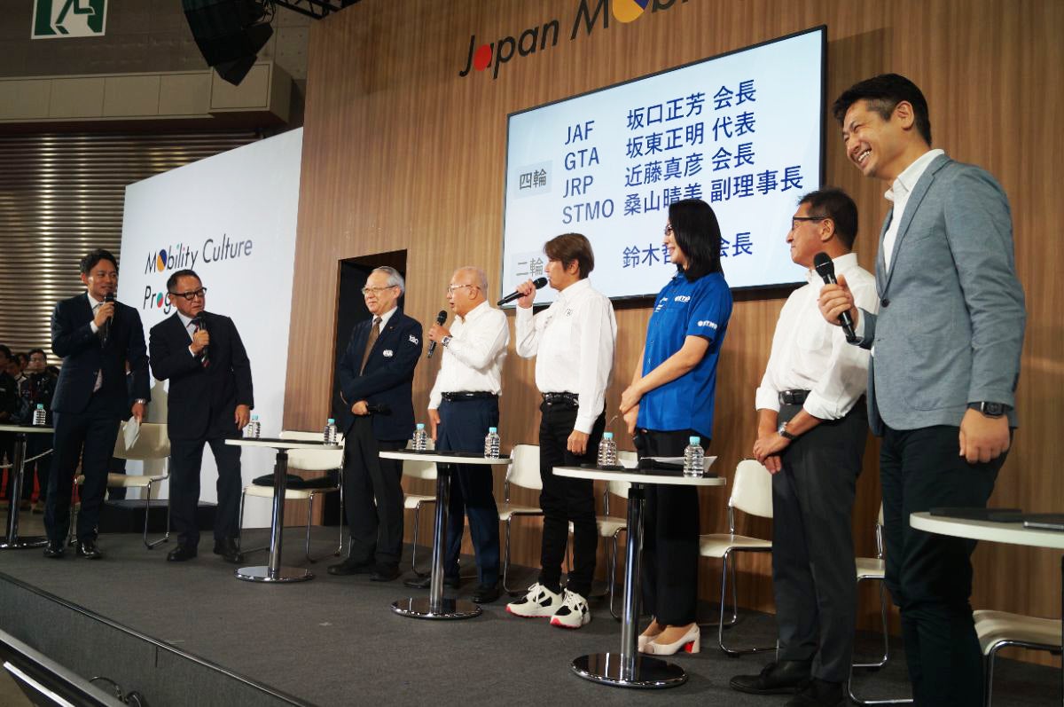 ステージに登壇したモータースポーツ団体のトップたち。左から、司会の森田京之介氏（トヨタイムズ）、豊田章男・日本自動車会議所会長、坂口正芳・JAF会長、坂東正明・GTアソシエイション会長、近藤真彦・日本レースプロモーション会長、桑山晴美・スーパー耐久未来機構副理事長、鈴木哲夫・日本モーターサイクルスポーツ協会会長、加地雅哉・日本自動車会議所モータースポーツ委員長