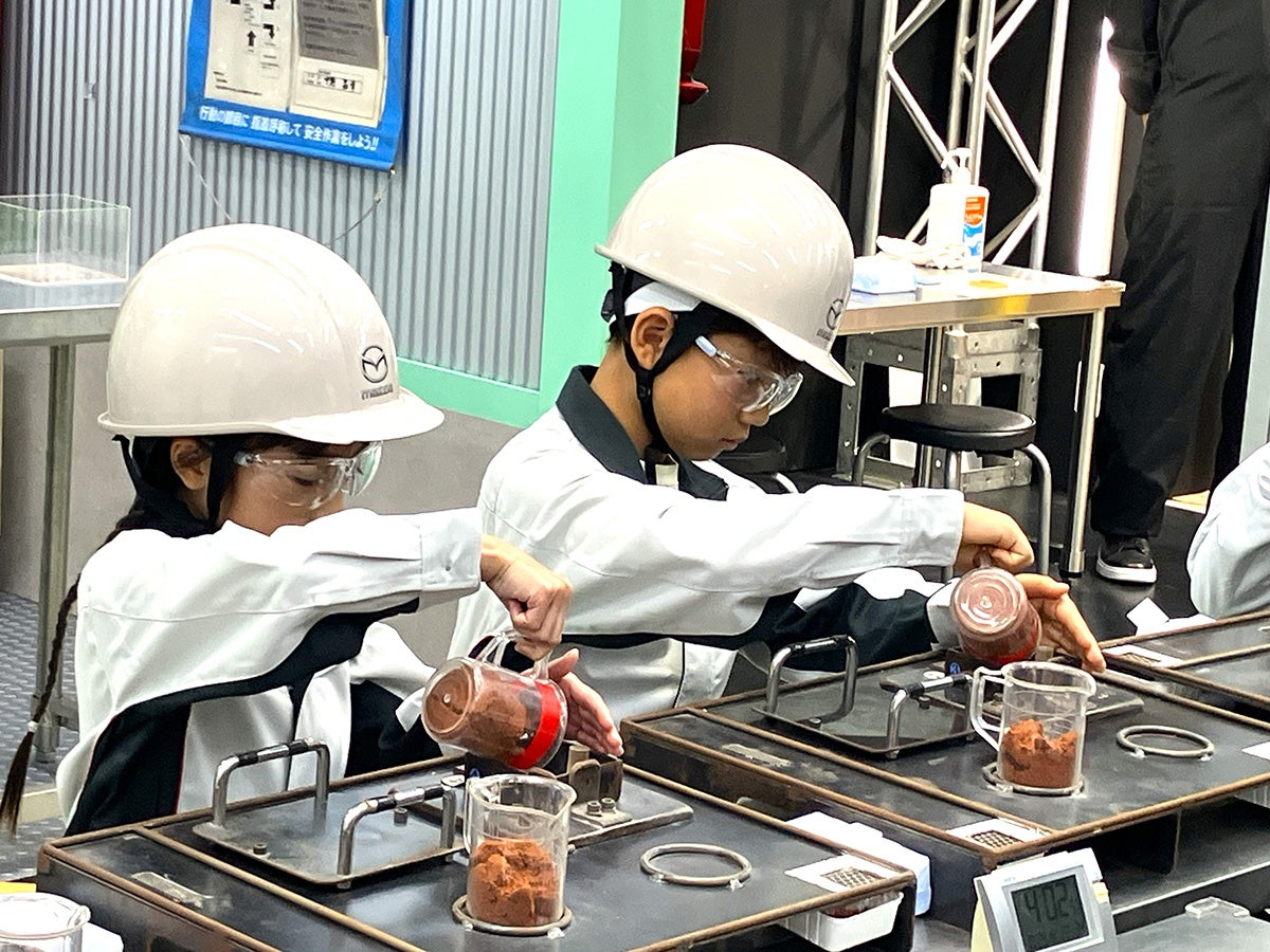 マツダブースでミニカーの砂型鋳造・磨き・塗装職人の仕事を体験する子ども