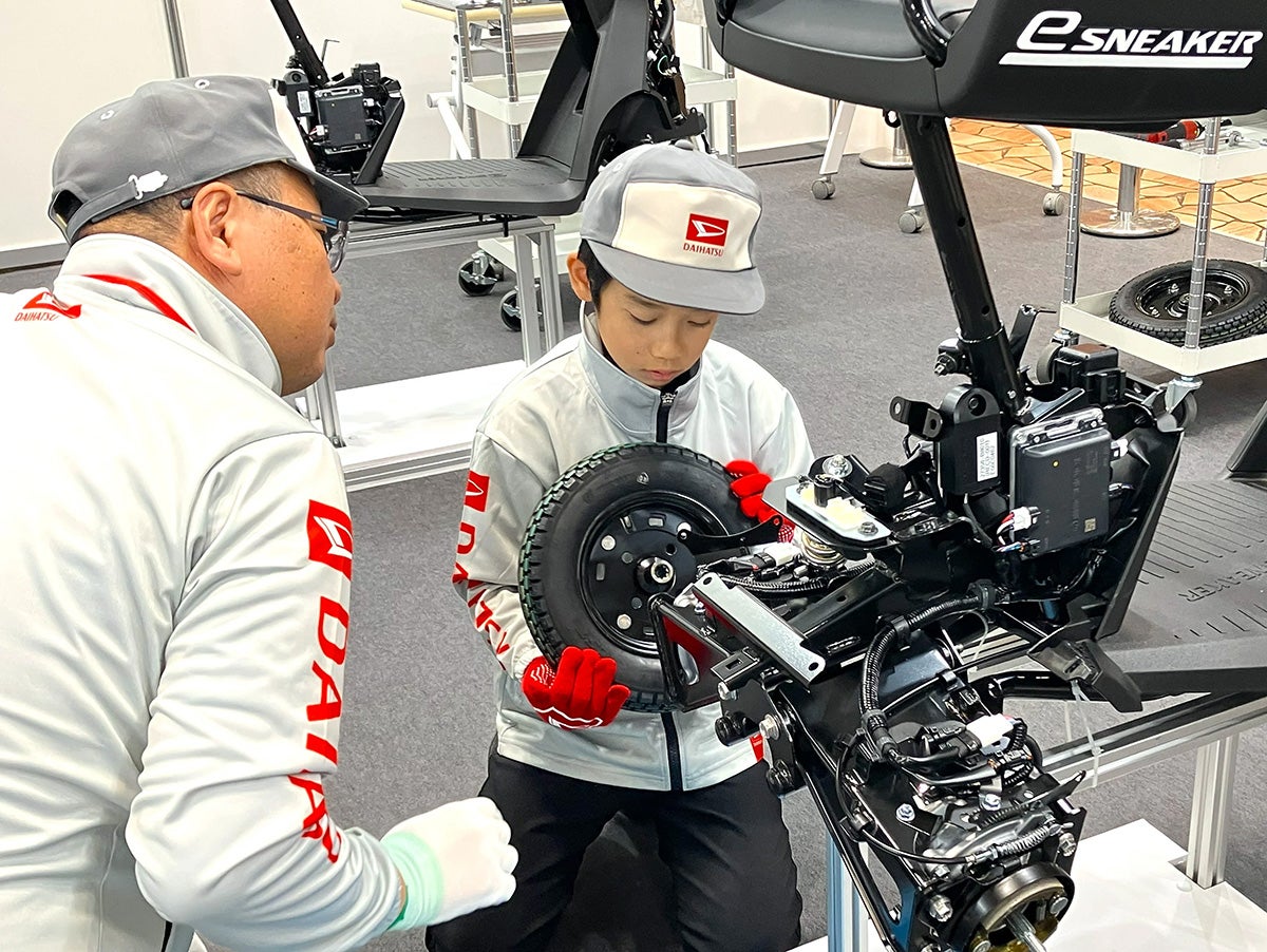 ダイハツブースで最新モビリティの組み立て体験をする子供