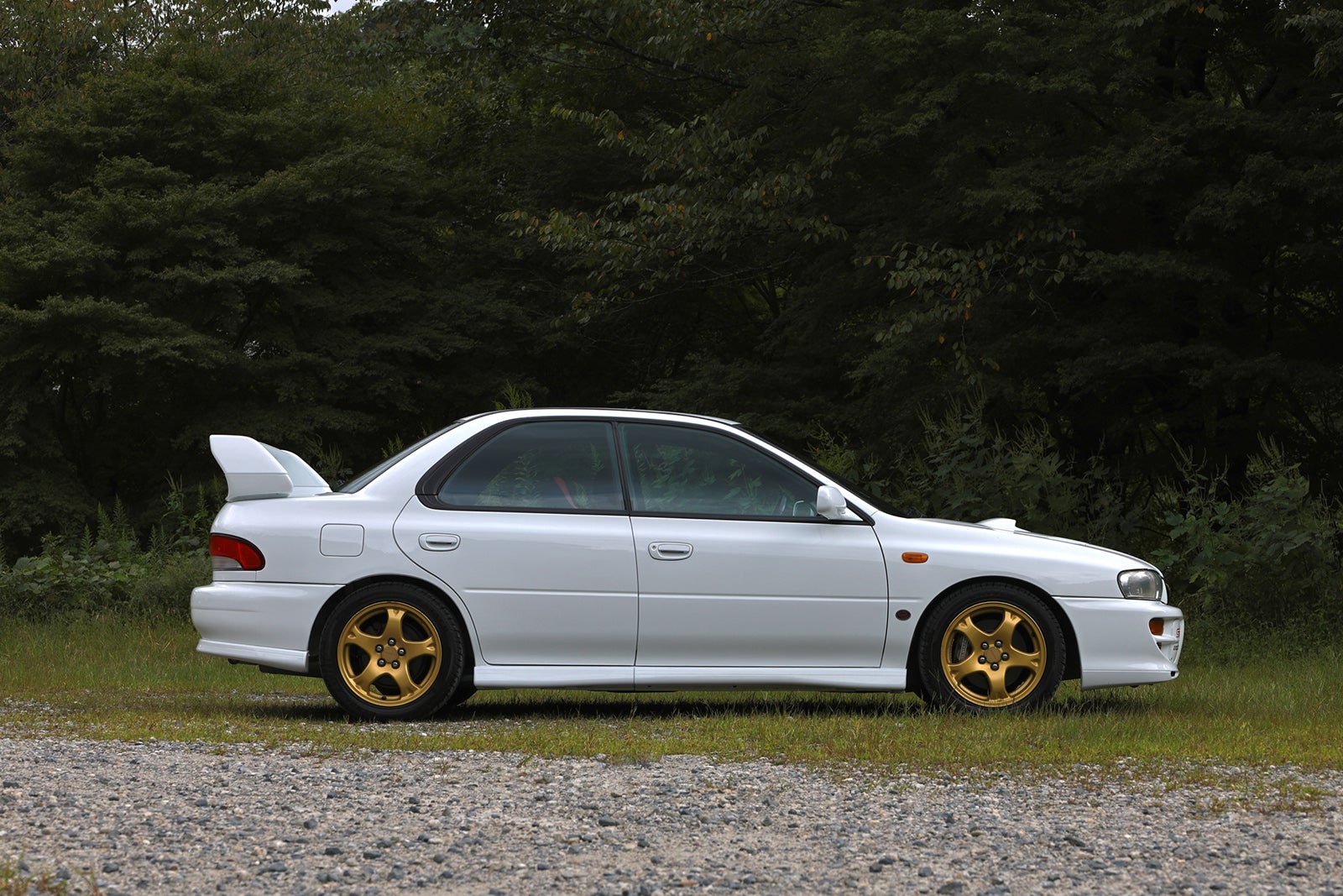 スバル・インプレッサWRX STi バージョンVのサイドビュー、ホワイトボディとゴールドホイール