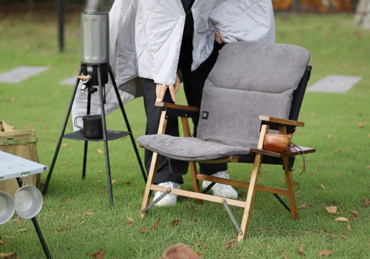 キャンプ場でアウトドアチェアをセットする人の写真