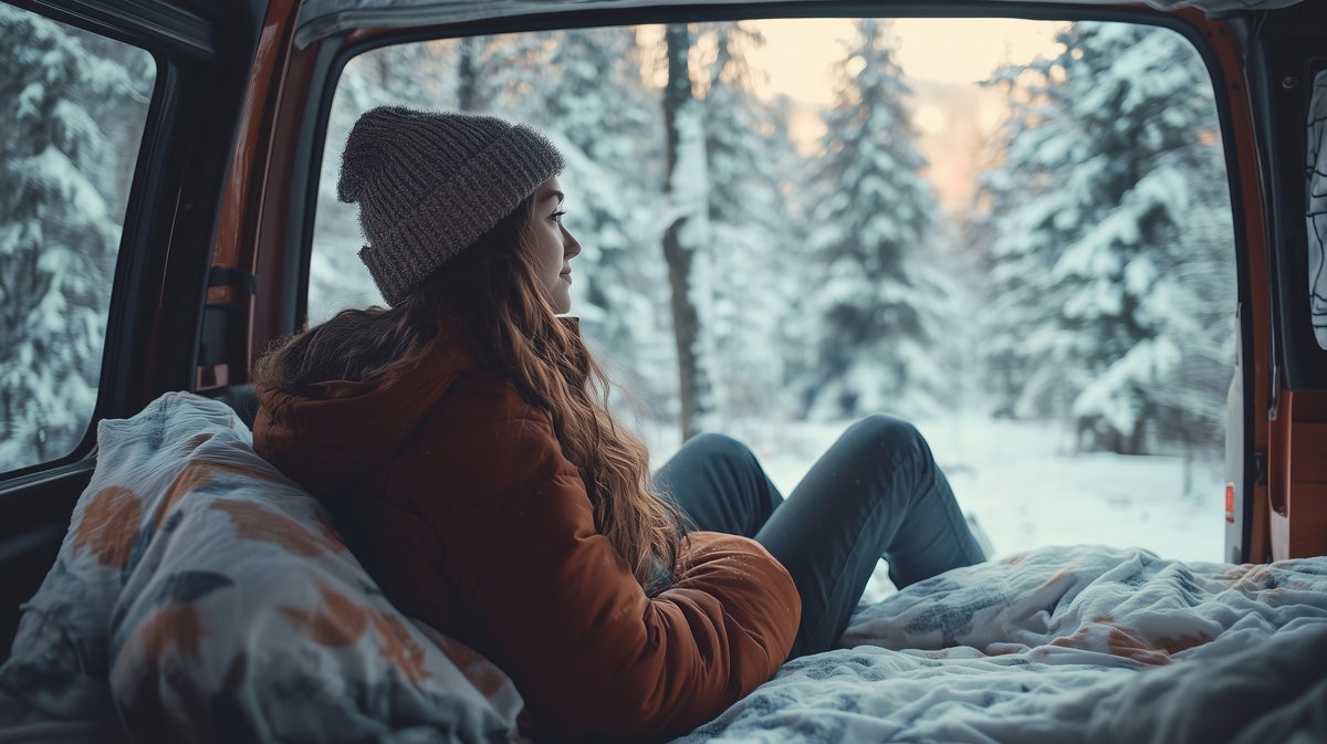 クルマのラゲッジルームから外の雪景色を眺める女性