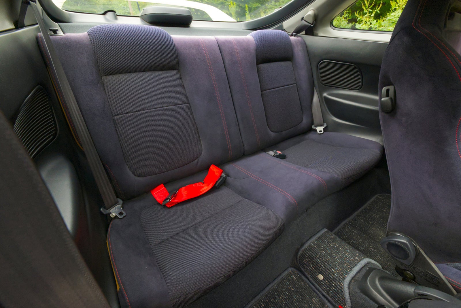黒色のスウェード調ファブリックに赤いステッチが施された後部座席。2名掛けのバケット形状になっている