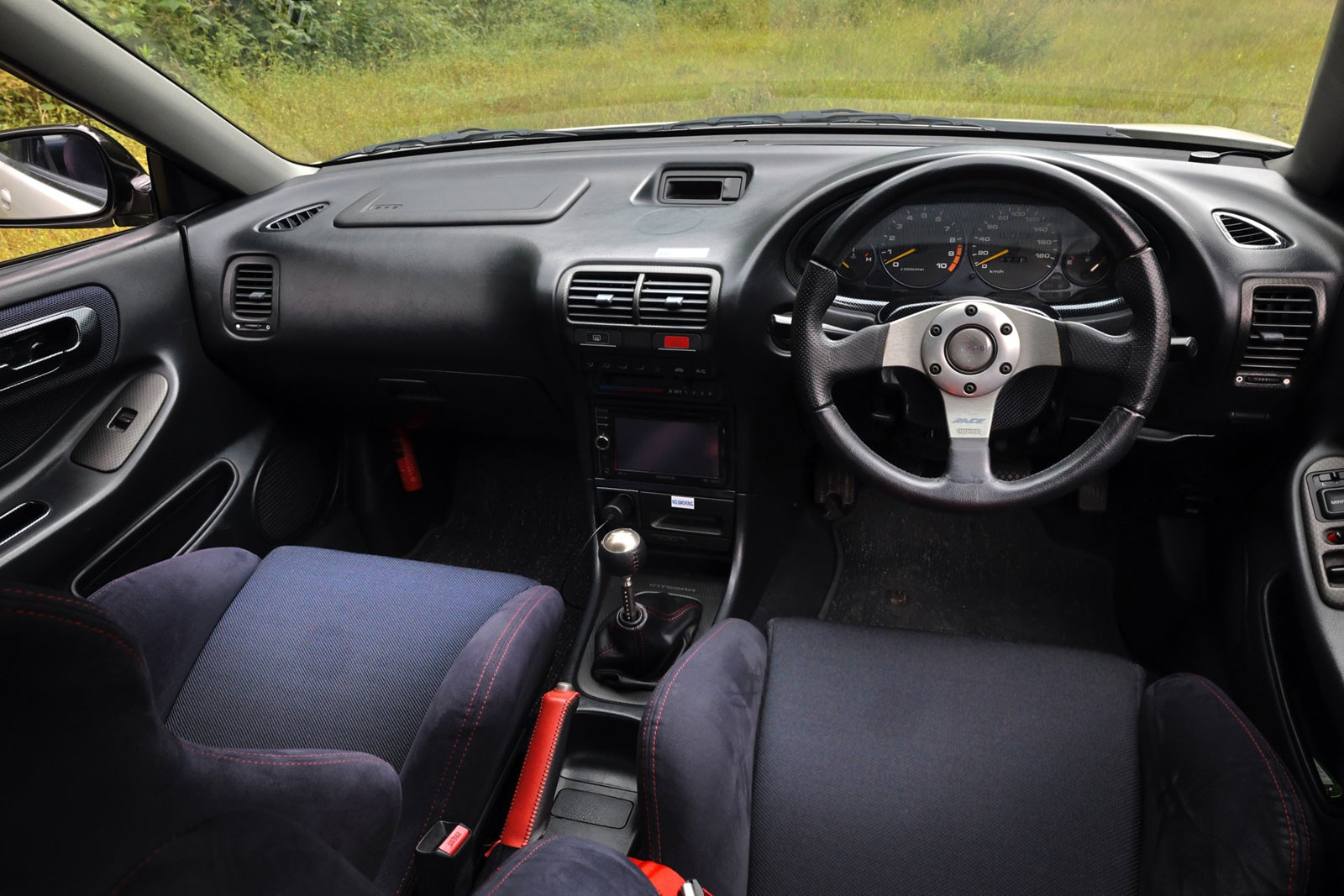 ホンダ インテグラ タイプR（初代）のコクピット。MOMOステアリングと5速マニュアルシフトが並ぶドライバーズシート、ワインディングを走るための純粋な操作系が際立つ