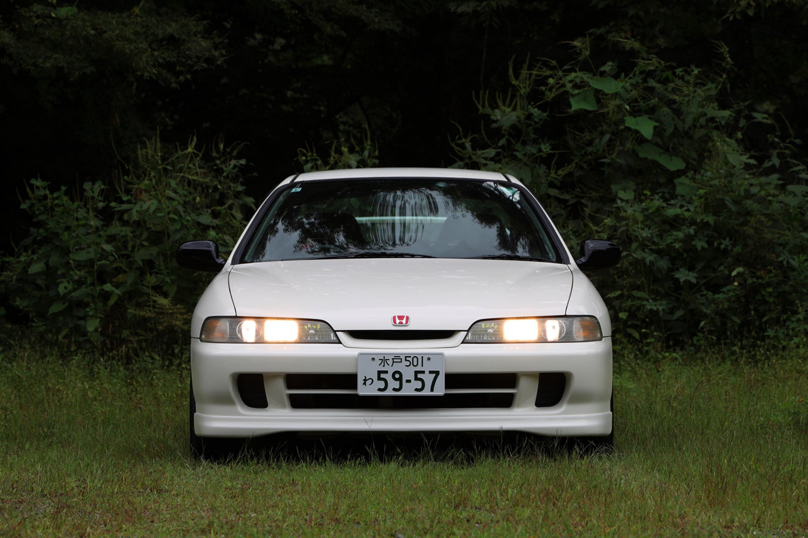 チャンピオンシップホワイトのホンダ・インテグラ タイプR（DC2）の正面写真。緑豊かな場所に停車している