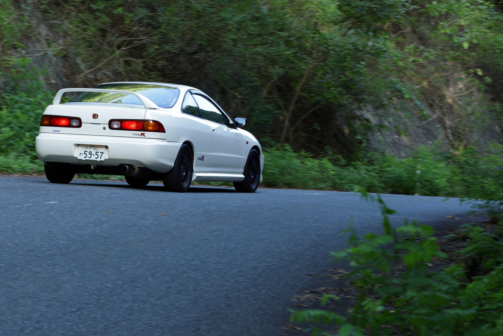 緑豊かな峠道（ワインディングロード）を走行するインテグラ タイプRの後ろ姿。コーナーを抜けていく様子