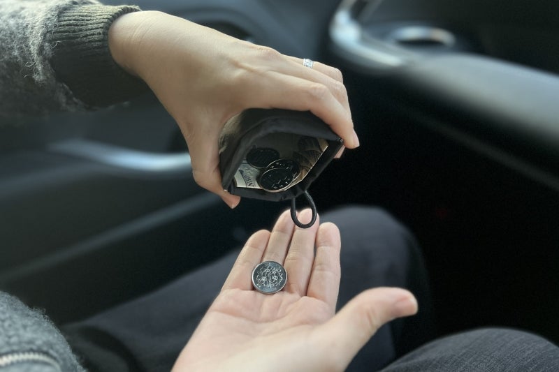 片手で開くフラットポーチからコインを取り出すイメージ