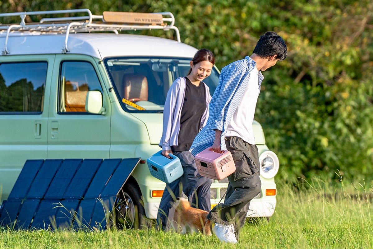 キャンプ場にて片手でポータブル電源を持ち運ぶ男女