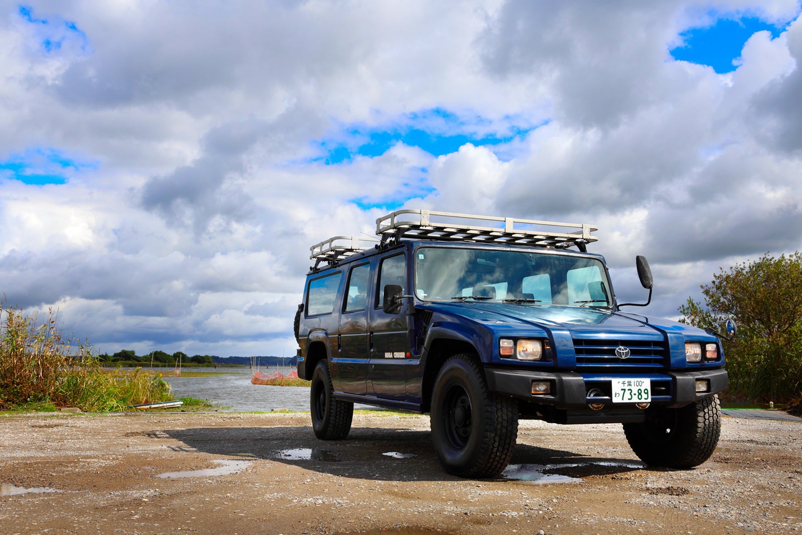 雲間の光を受けるブルーのトヨタ・メガクルーザー、左前3/4外観