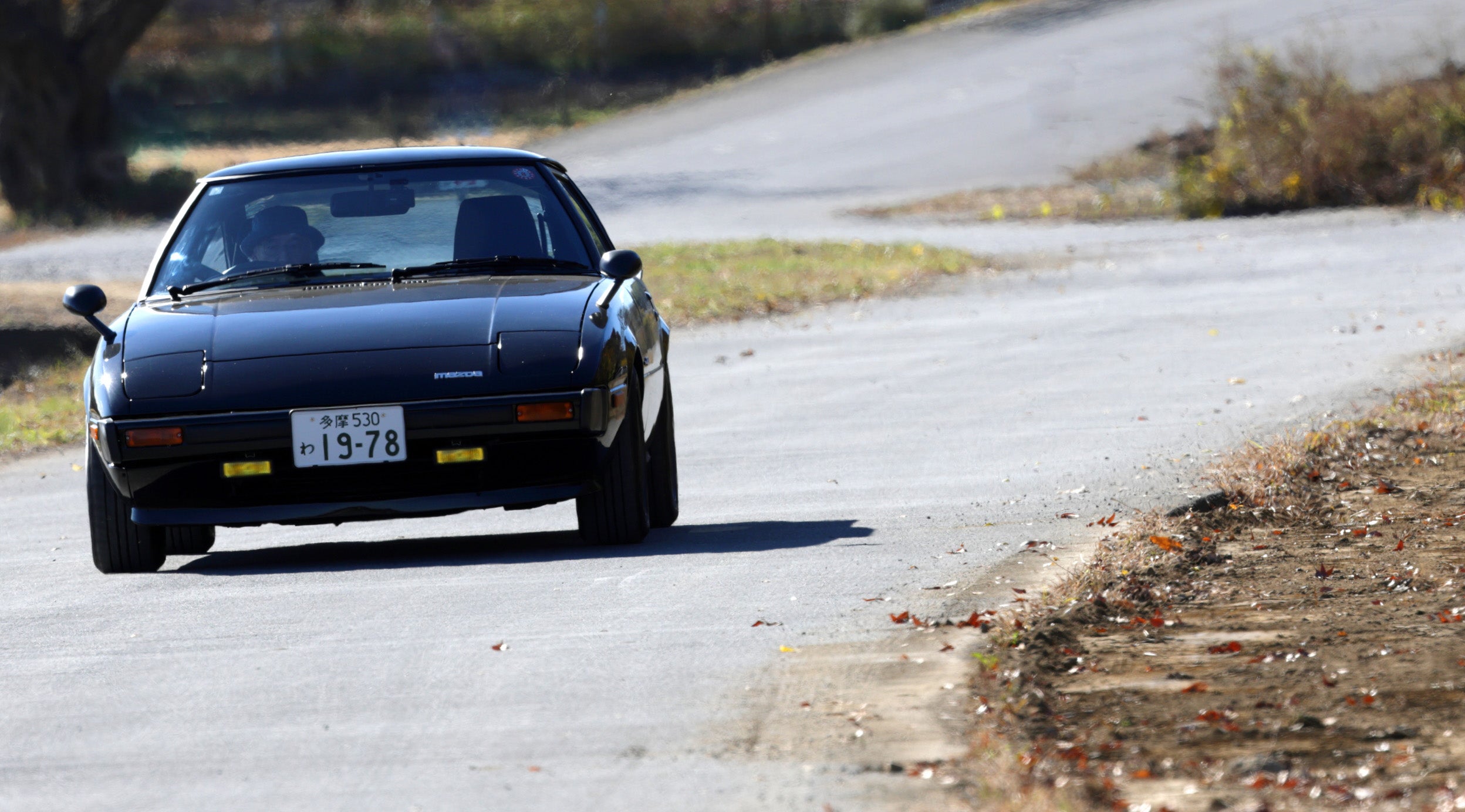 ワインディングロードを走行するSA22C型マツダRX-7のフロントビュー