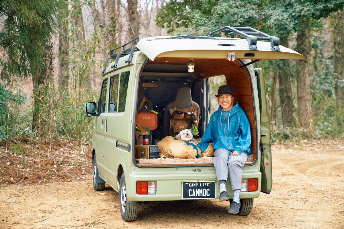 軽バンのラゲッジドアを開けて、ラゲッジに座ってくつろぐ女性