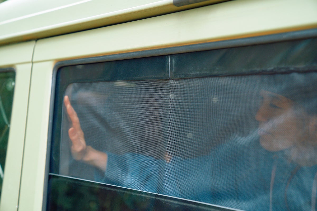 クルマの窓にメッシュシェードをセットしている風景