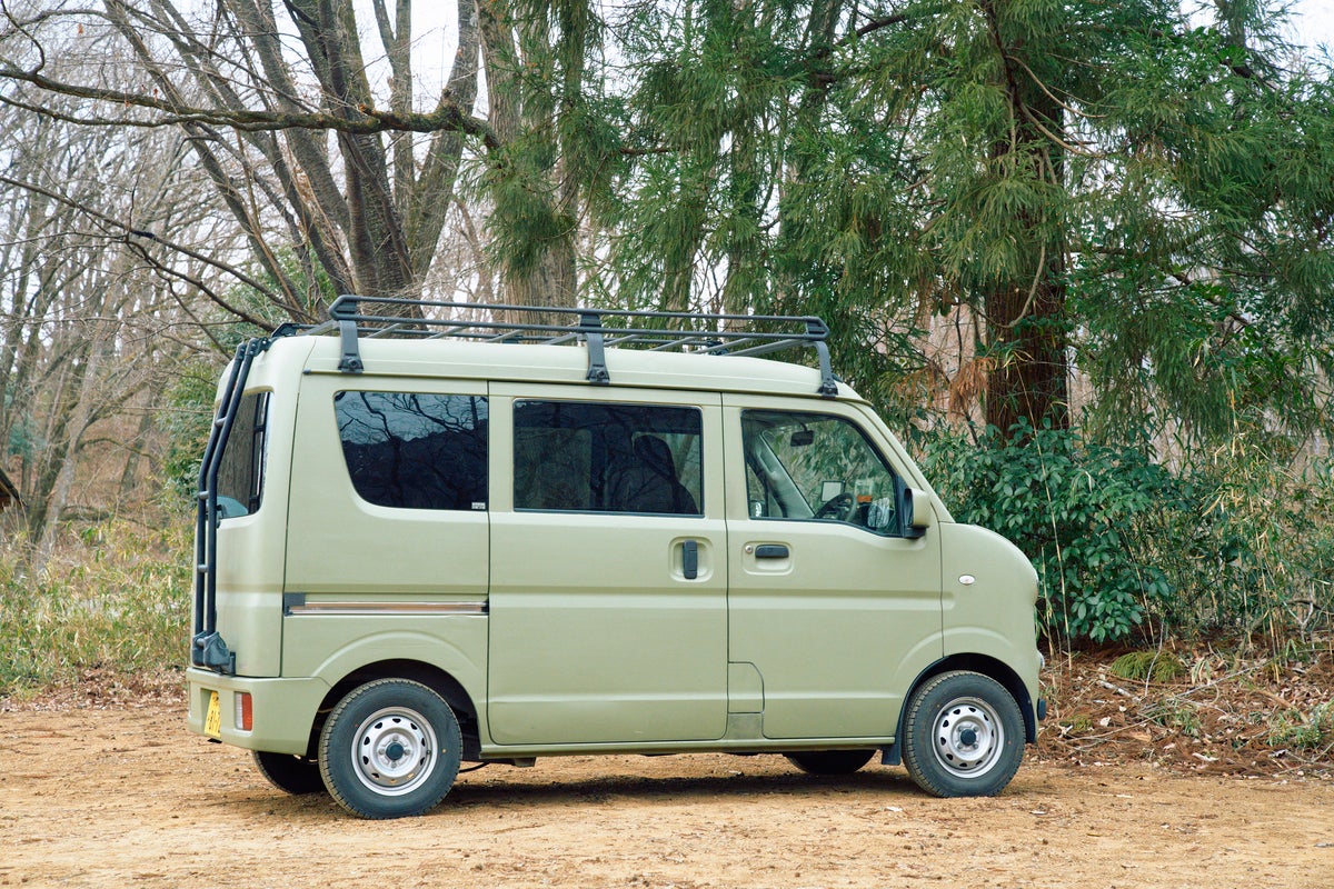 土の上に駐車している軽バンの横向き写真