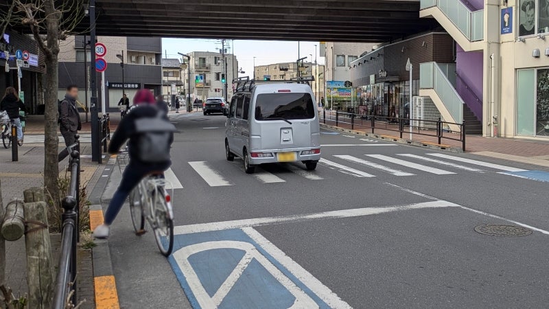 横断歩道を渡ろうとする歩行者の手前で一時停止する自転車
