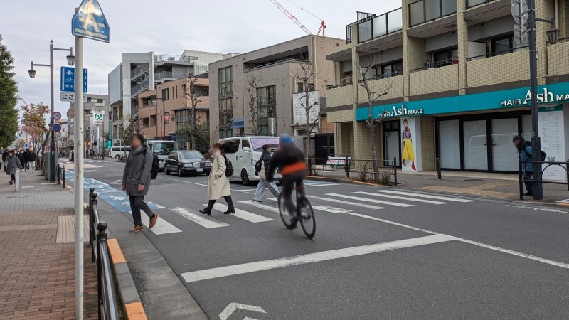 横断する歩行者の間をすり抜けるように走っていく自転車