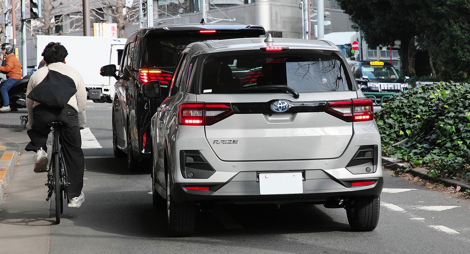 車道を走る自転車の横を走行するクルマの写真