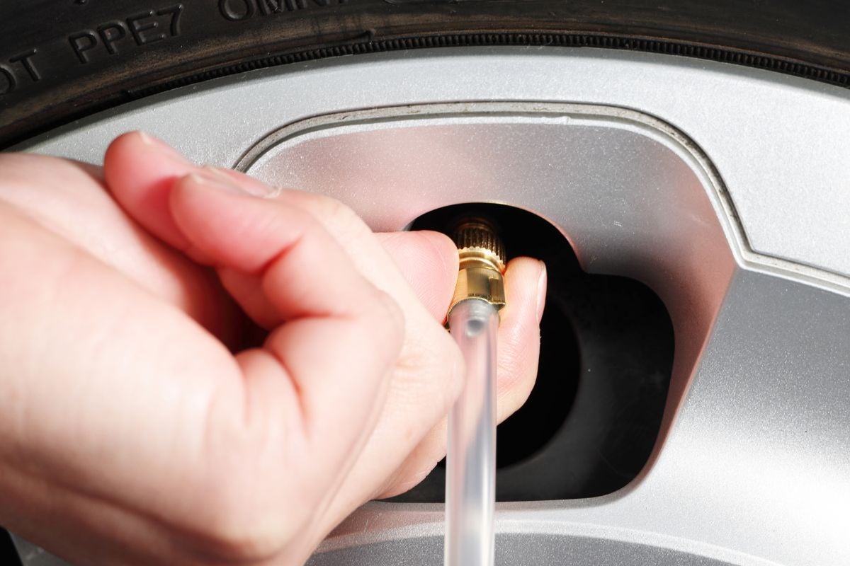 タイヤのバルブにホースを装着している手元のアップ