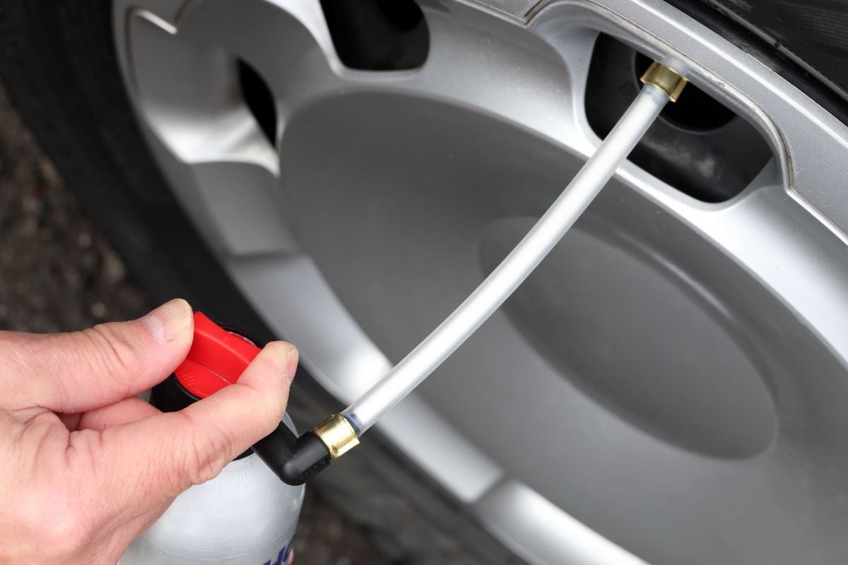 パンク修理剤のボタンをひねって薬剤を注入している様子