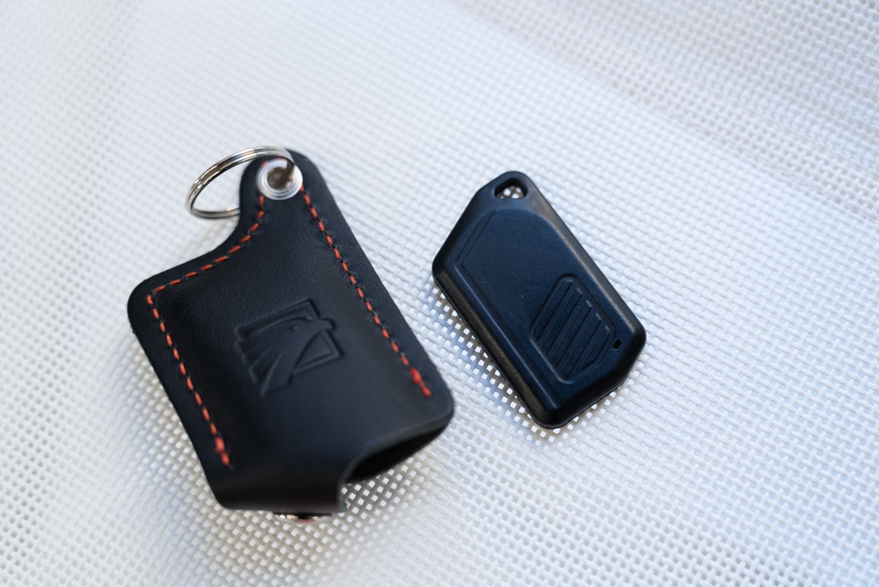 オーサーアラームの認証キー「キーフォブ」と車のスマートキーのサイズ比較。持ち運びに便利なコンパクトな設計。