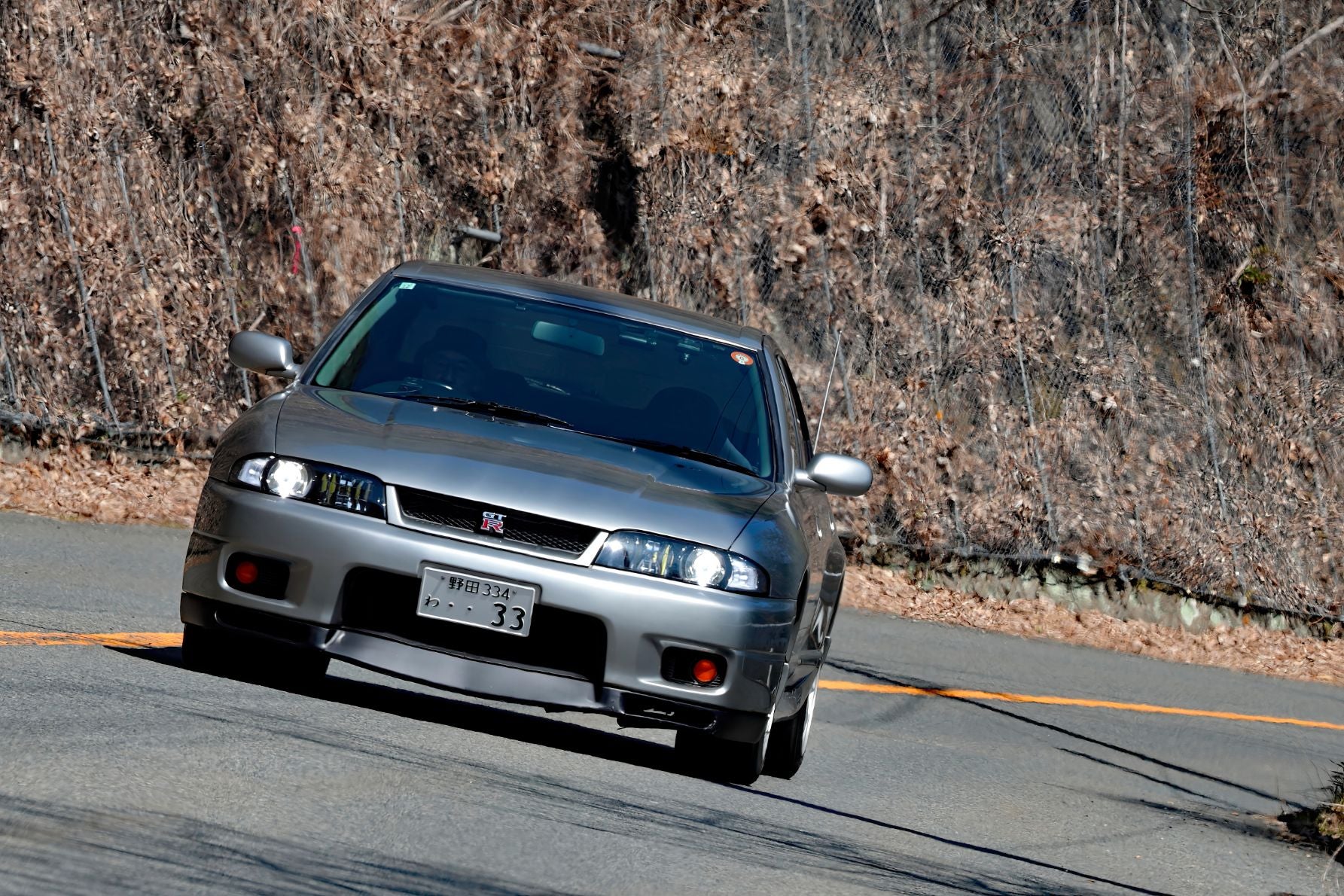 日産スカイラインGT-R オーテックバージョン（BCNR33型改）がワインディングをコーナリングする様子