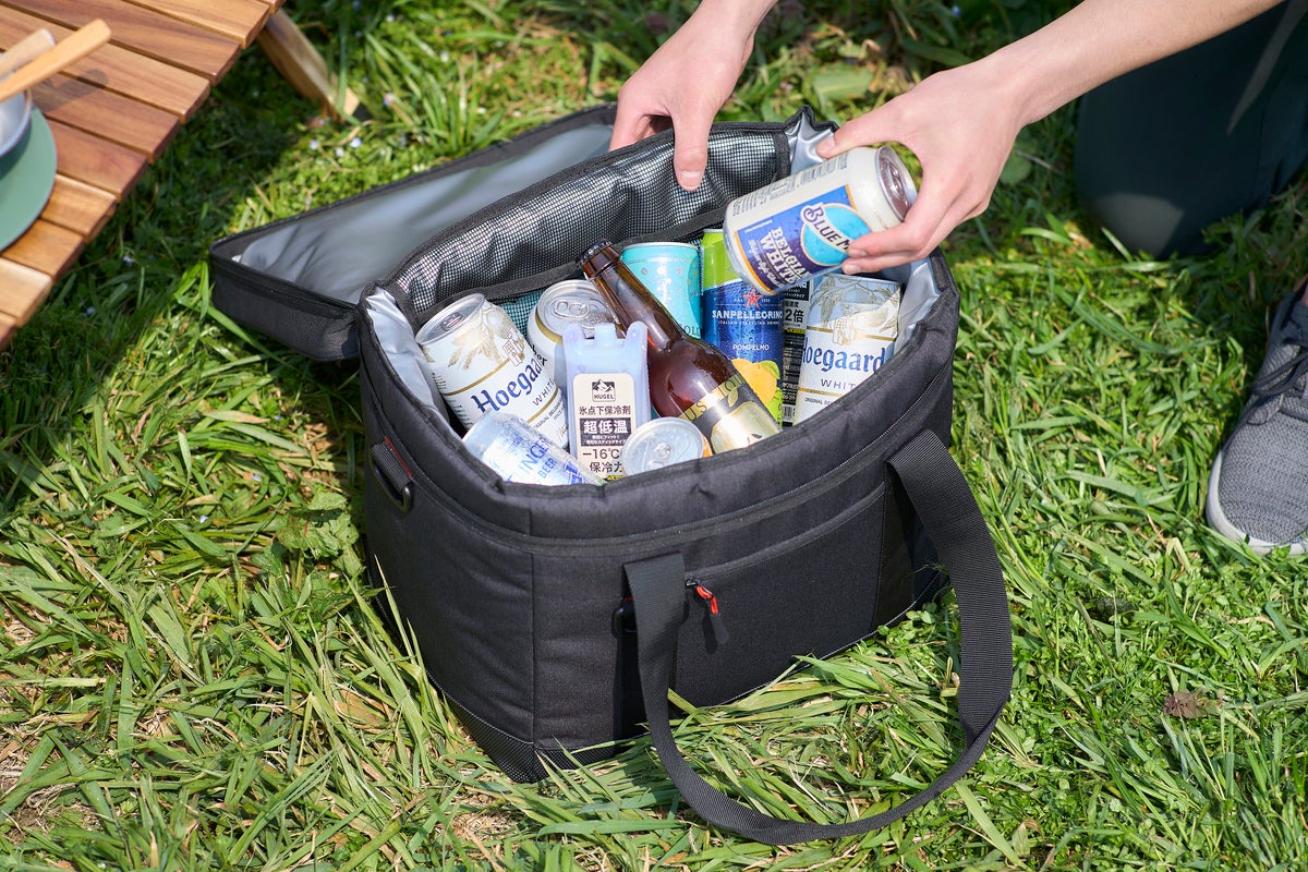 野原でクーラーバッグを開けて飲み物を取り出している写真