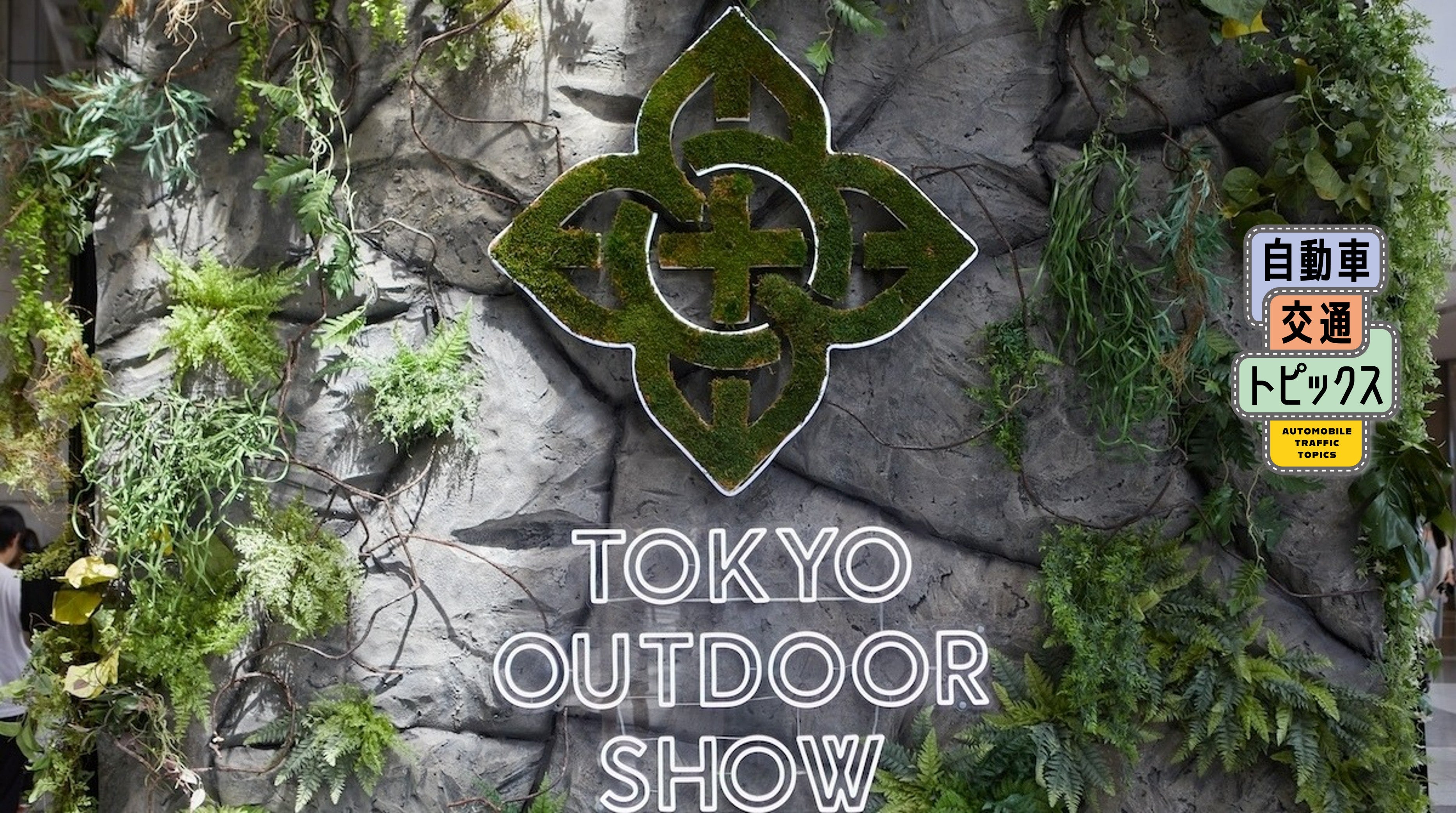 岩をモチーフにした背景に、苔で作られたTOKYO OUTDOOR SHOWのロゴマークと白いネオン文字が施されたオブジェ。周囲にシダや蔦などの植物が飾られている