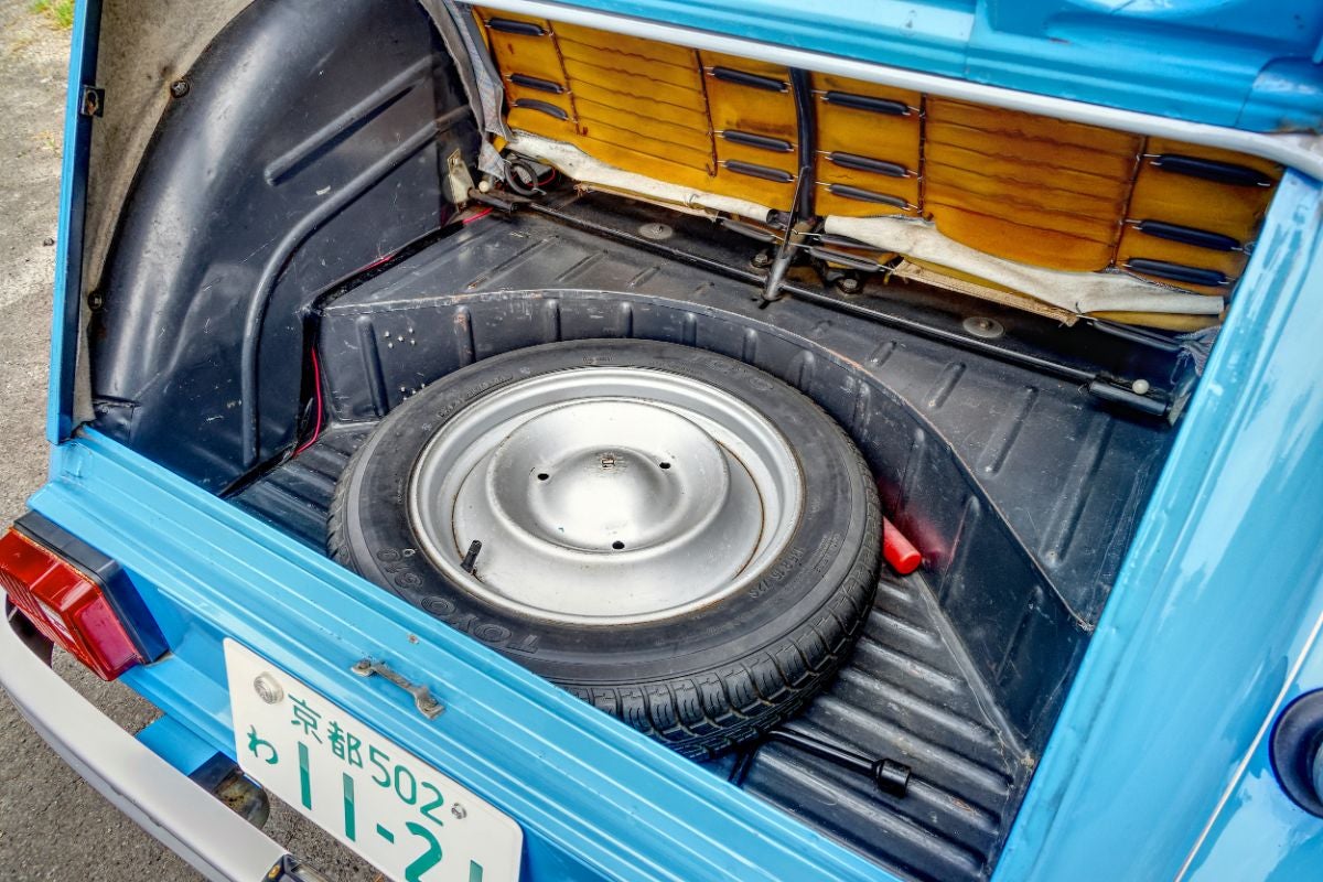 開いたトランクの内部。床面にむき出しで収納されているスペアタイヤと、むき出しのシート裏のバネが見える