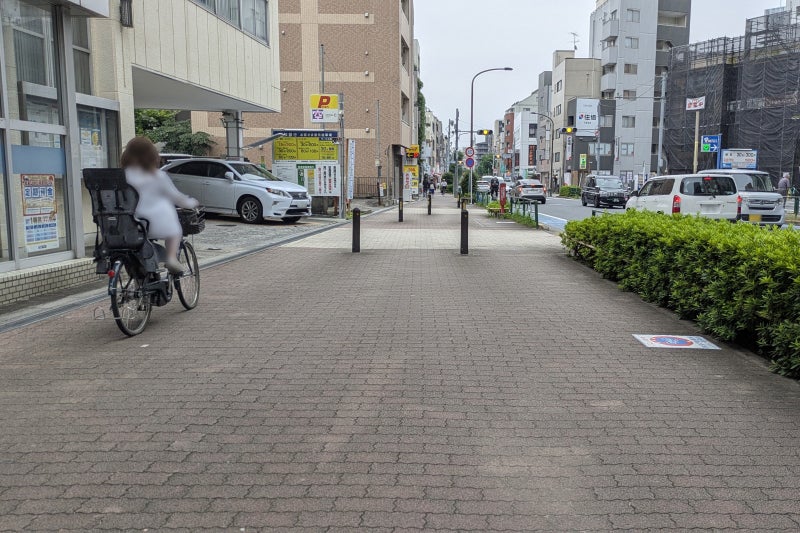 広めの歩道を建物寄りに走る自転車