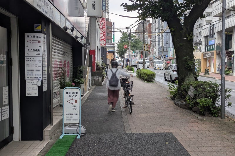 歩道で自転車を押し歩きする人