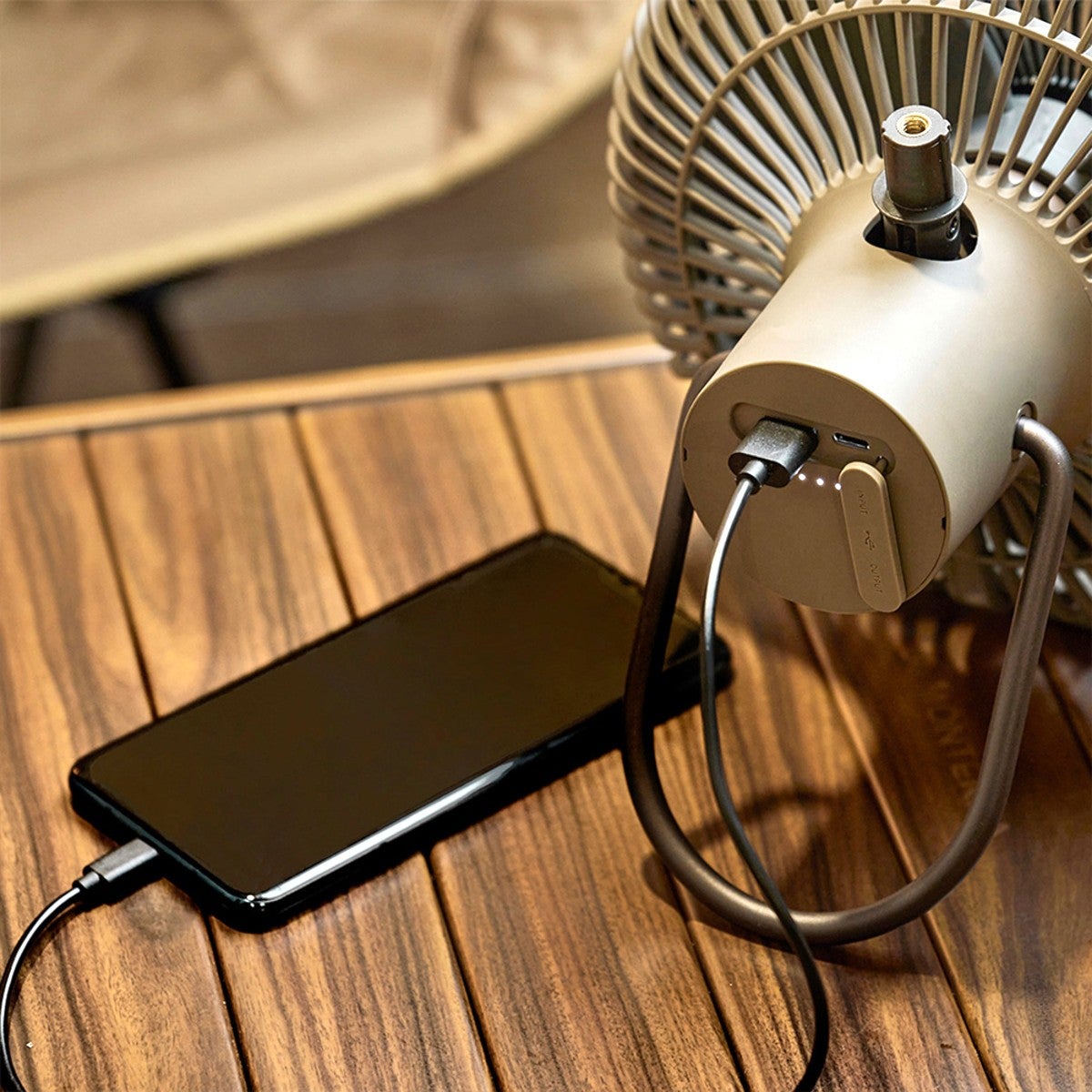 テーブル上の扇風機背面からスマートフォンへ給電（モバイルバッテリー機能）している様子