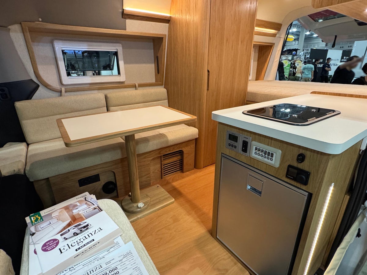コンロ付きキッチンとダイネットテーブルを備えたバンコンの車内インテリア